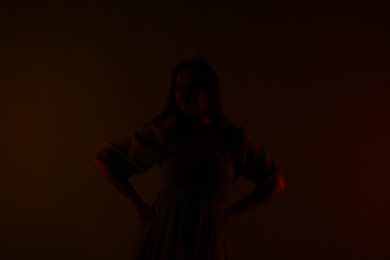 Photo of Silhouette of woman with crown on dark brown background