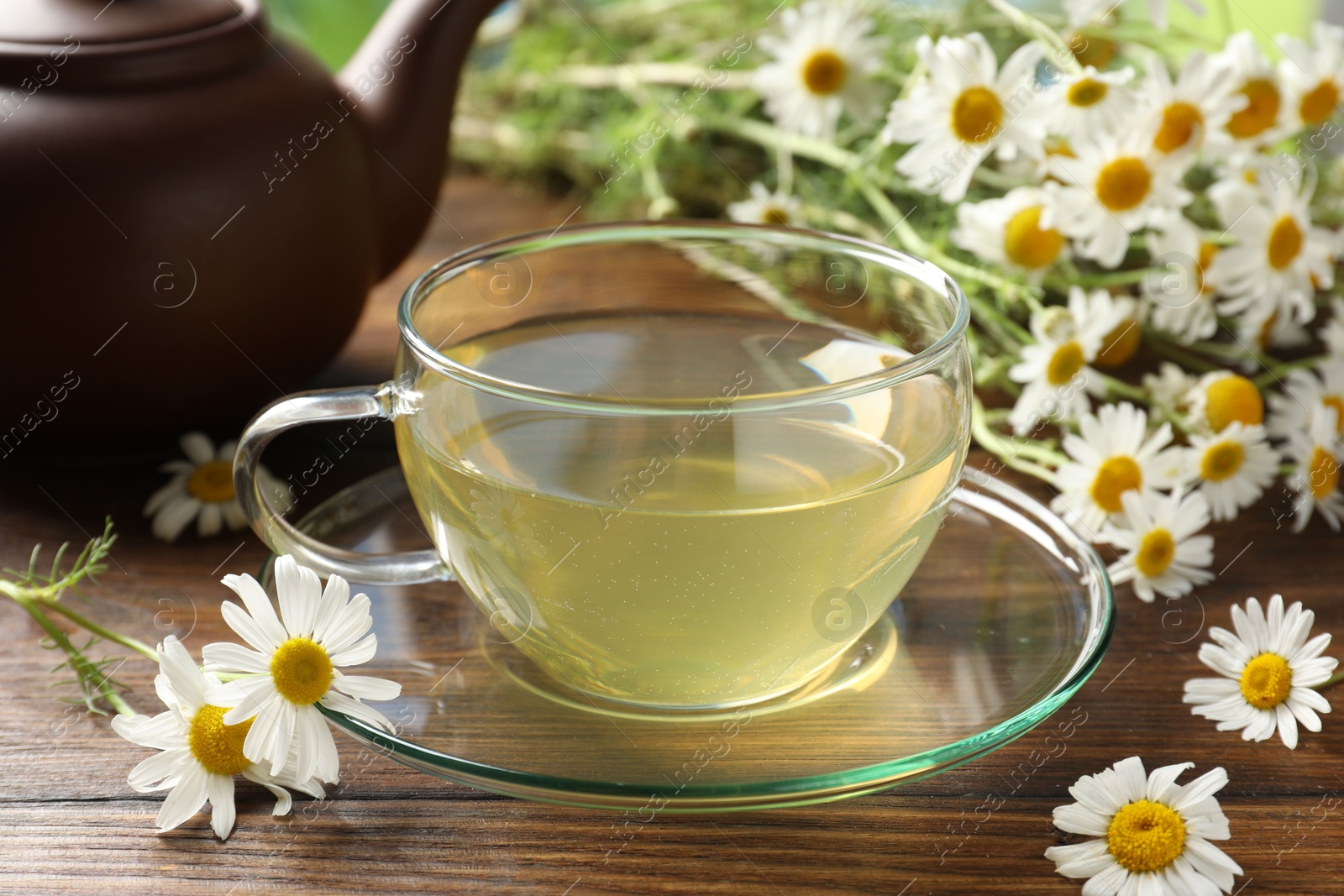 Tasty chamomile tea and flowers on wooden table, closeup Photo of Tasty chamomile tea and flowers on wooden table, closeup