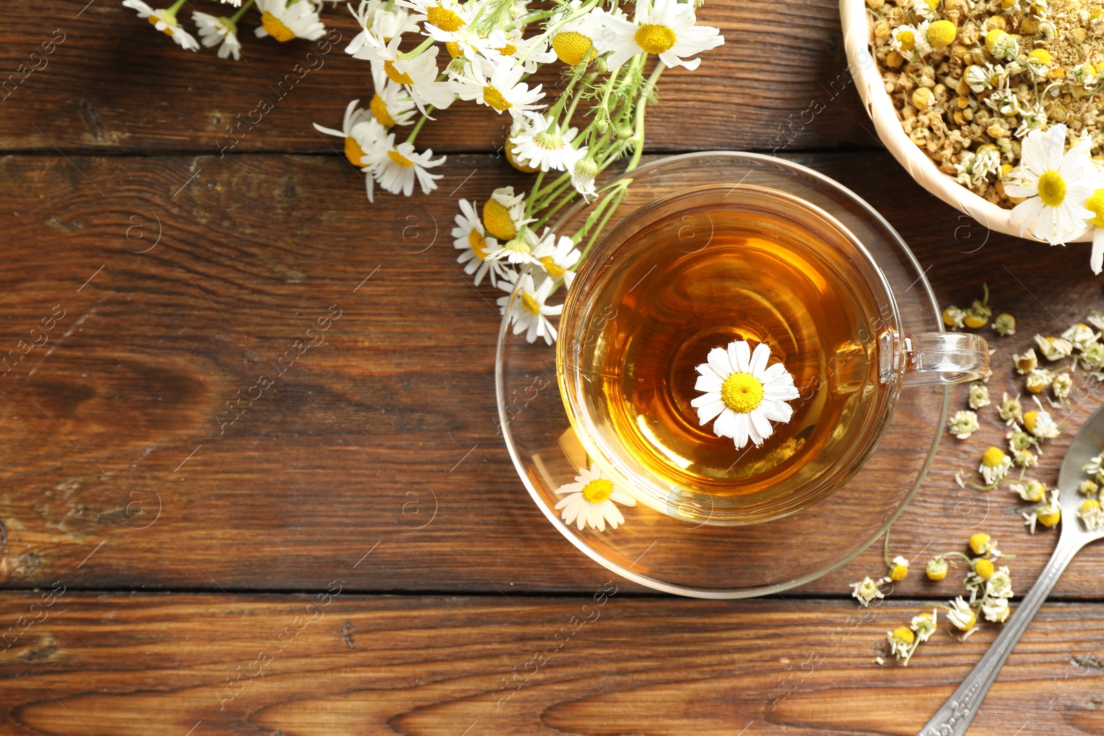 Tasty chamomile tea and flowers on wooden table, flat lay. Space for text Photo of Tasty chamomile tea and flowers on wooden table, flat lay. Space for text