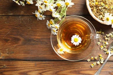 Photo of Tasty chamomile tea and flowers on wooden table, flat lay. Space for text