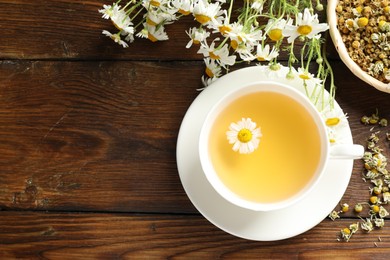 Photo of Tasty chamomile tea and flowers on wooden table, flat lay. Space for text