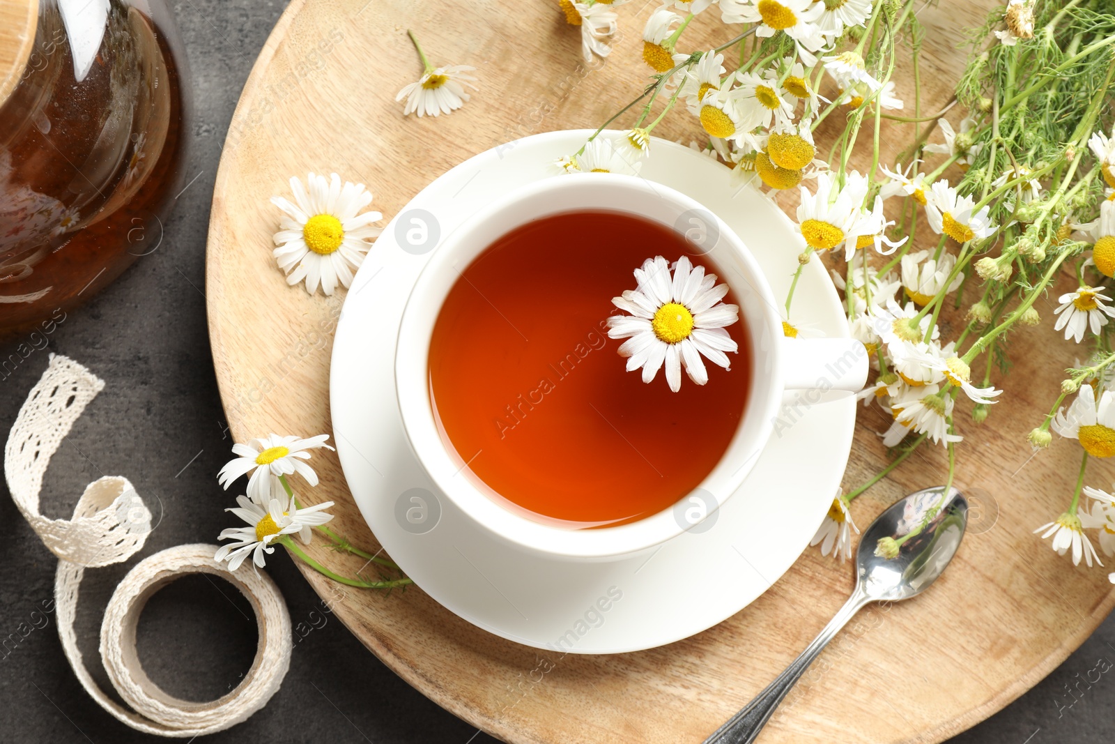Tasty chamomile tea and flowers on black table, flat lay Photo of Tasty chamomile tea and flowers on black table, flat lay