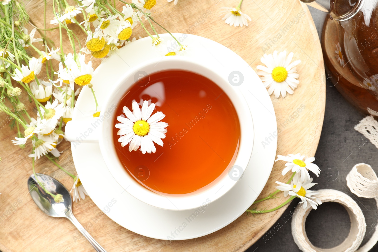 Tasty chamomile tea and flowers on black table, flat lay Photo of Tasty chamomile tea and flowers on black table, flat lay