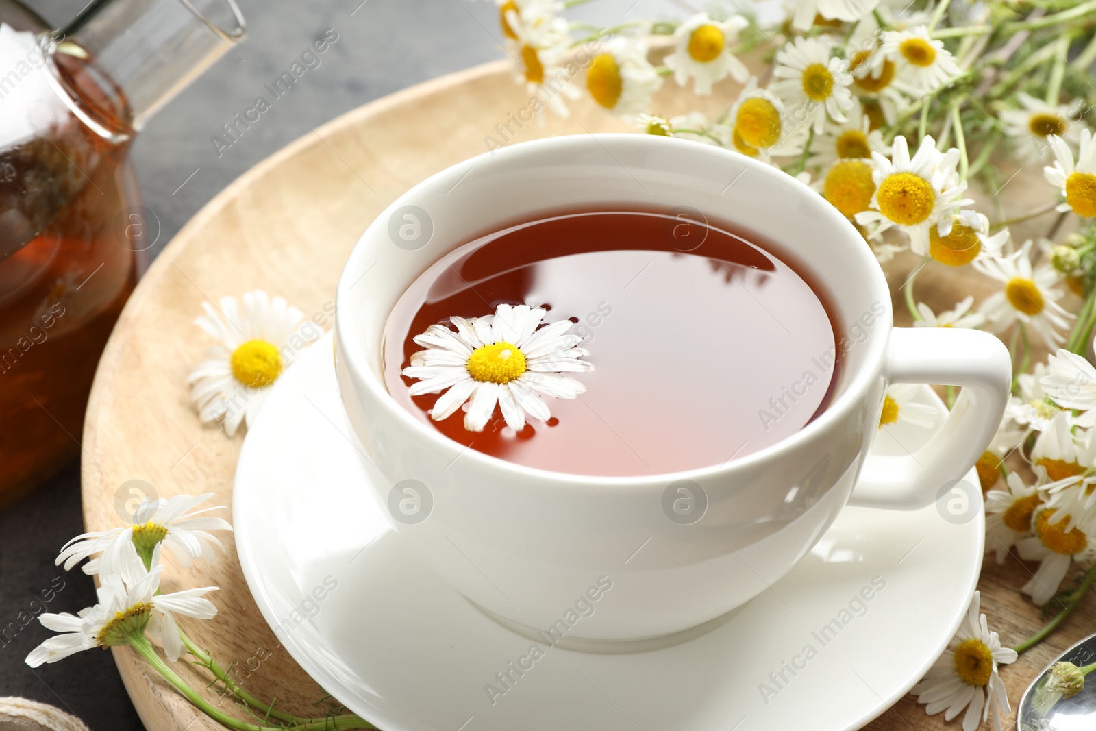 Tasty chamomile tea and flowers on black table, closeup Photo of Tasty chamomile tea and flowers on black table, closeup