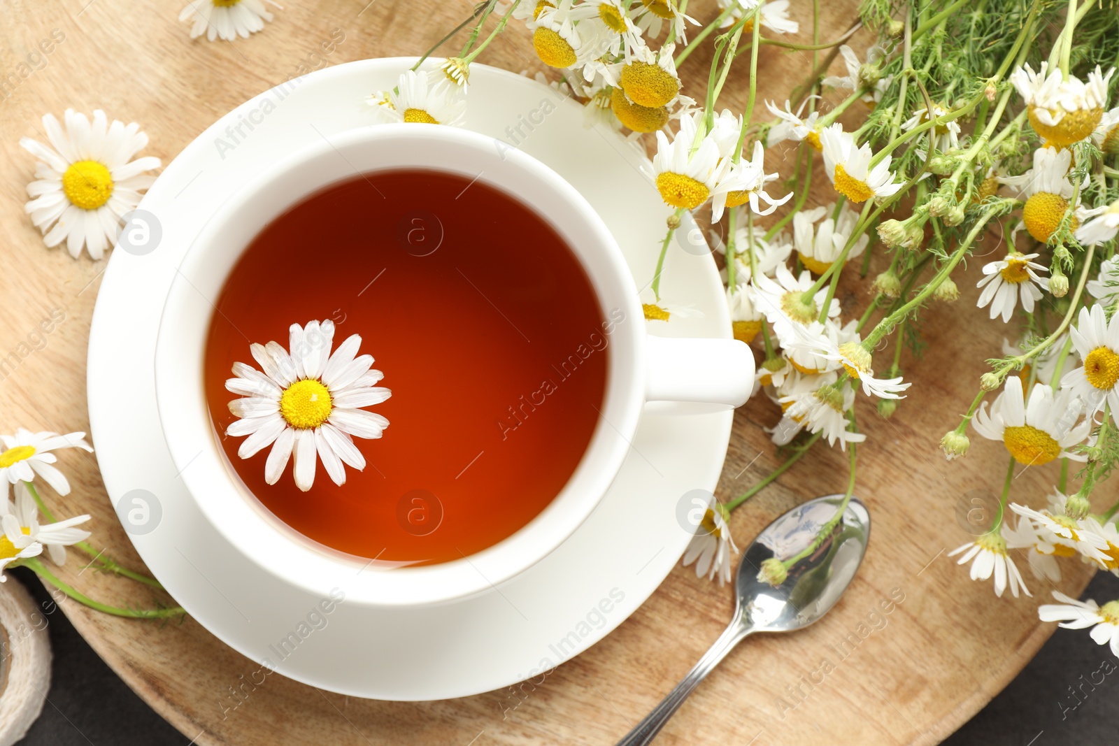 Tasty chamomile tea and flowers on black table, flat lay Photo of Tasty chamomile tea and flowers on black table, flat lay