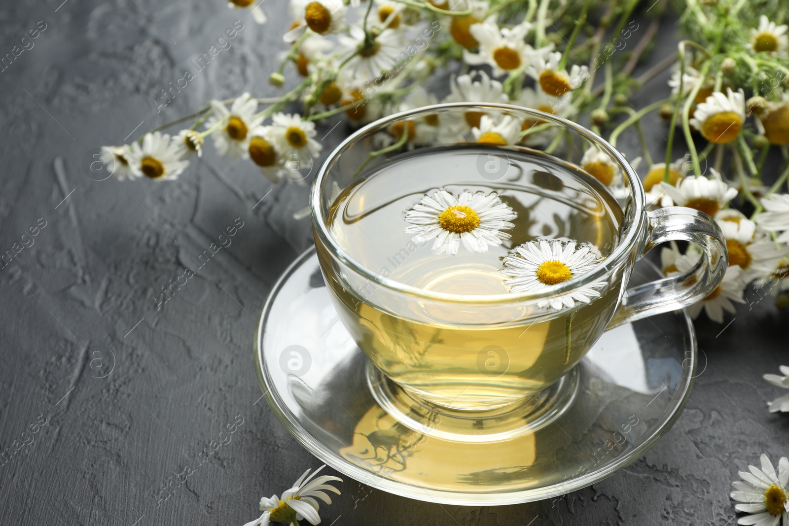 Tasty chamomile tea and flowers on black table, closeup. Space for text Photo of Tasty chamomile tea and flowers on black table, closeup. Space for text