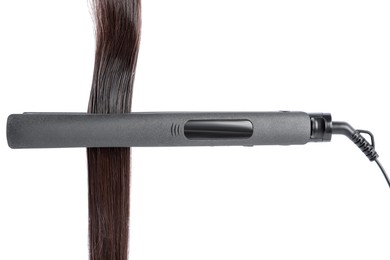Photo of Straightener with brown hair lock isolated on white