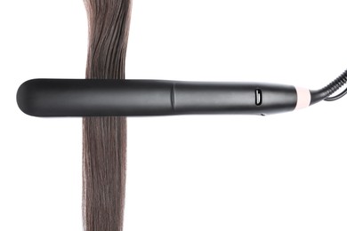 Photo of Straightener with brown hair lock isolated on white