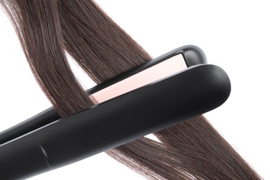 Photo of Straightener with brown hair locks isolated on white