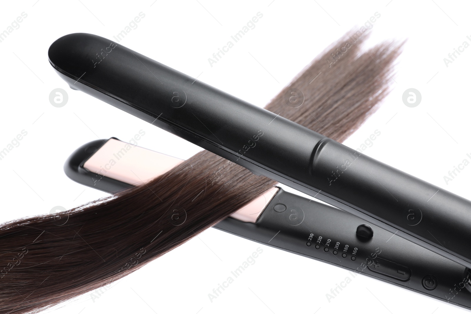 Photo of Straightener with brown hair lock isolated on white