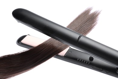 Photo of Straightener with brown hair lock isolated on white