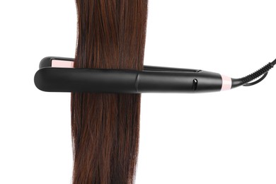 Photo of Straightener with brown hair lock isolated on white