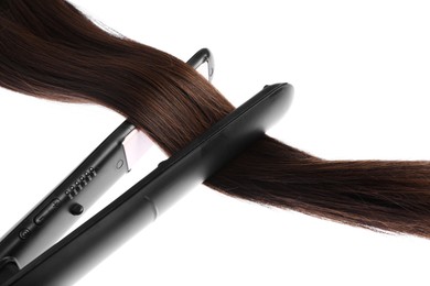 Photo of Straightener with brown hair lock isolated on white
