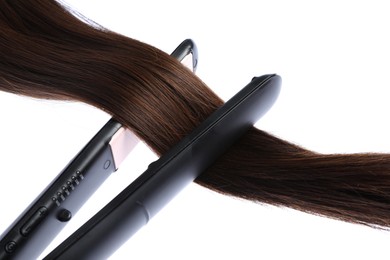 Photo of Straightener with brown hair lock isolated on white