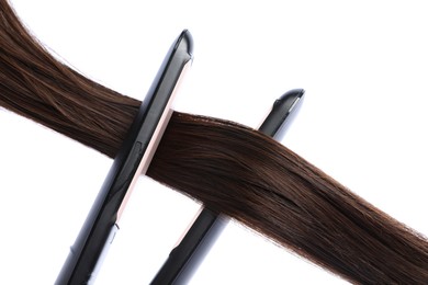 Photo of Straightener with brown hair lock isolated on white