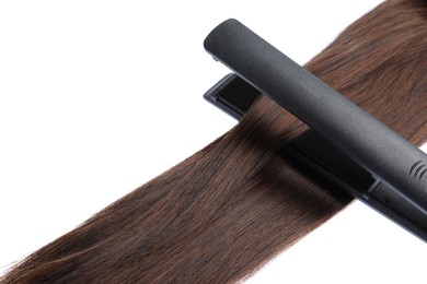 Photo of Straightener with brown hair lock isolated on white