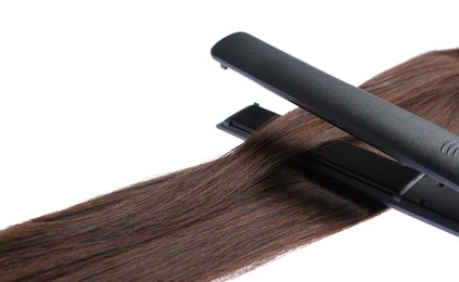 Photo of Straightener with brown hair lock isolated on white