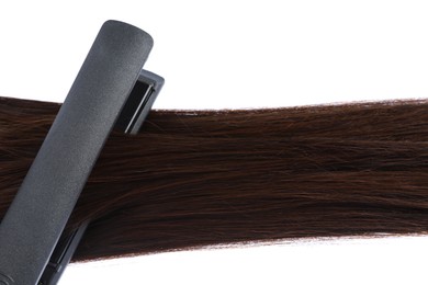 Photo of Straightener with brown hair lock isolated on white