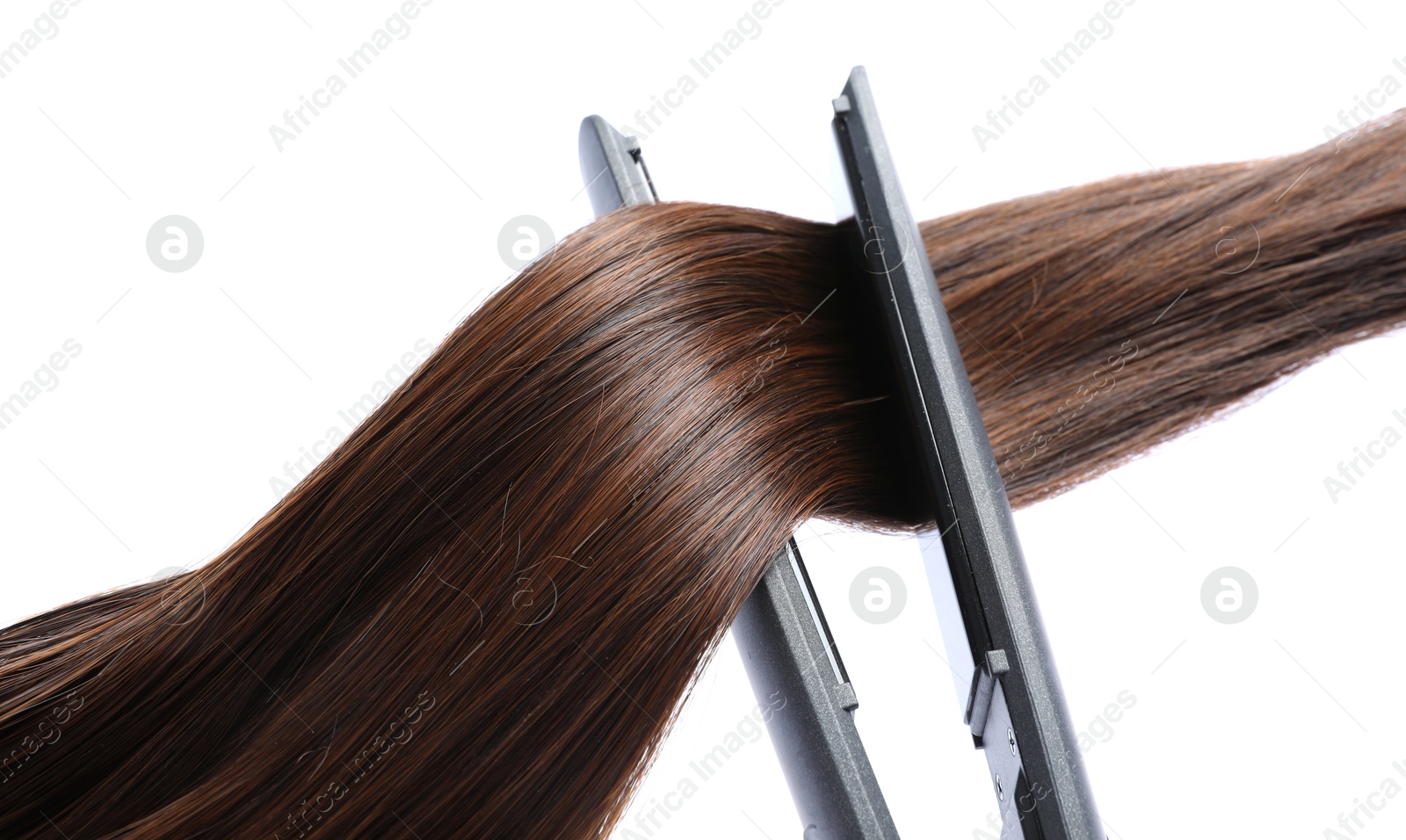 Photo of Straightener with brown hair lock isolated on white