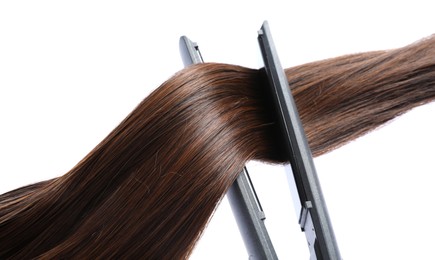 Photo of Straightener with brown hair lock isolated on white