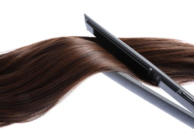 Photo of Straightener with brown hair lock isolated on white