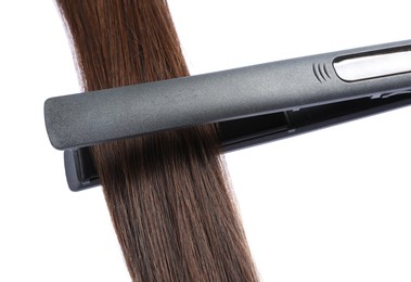 Photo of Straightener with brown hair lock isolated on white