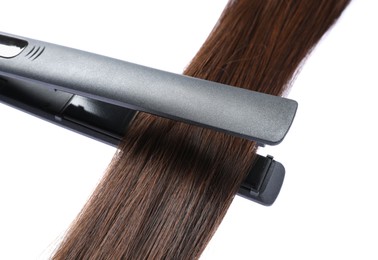 Photo of Straightener with brown hair lock isolated on white