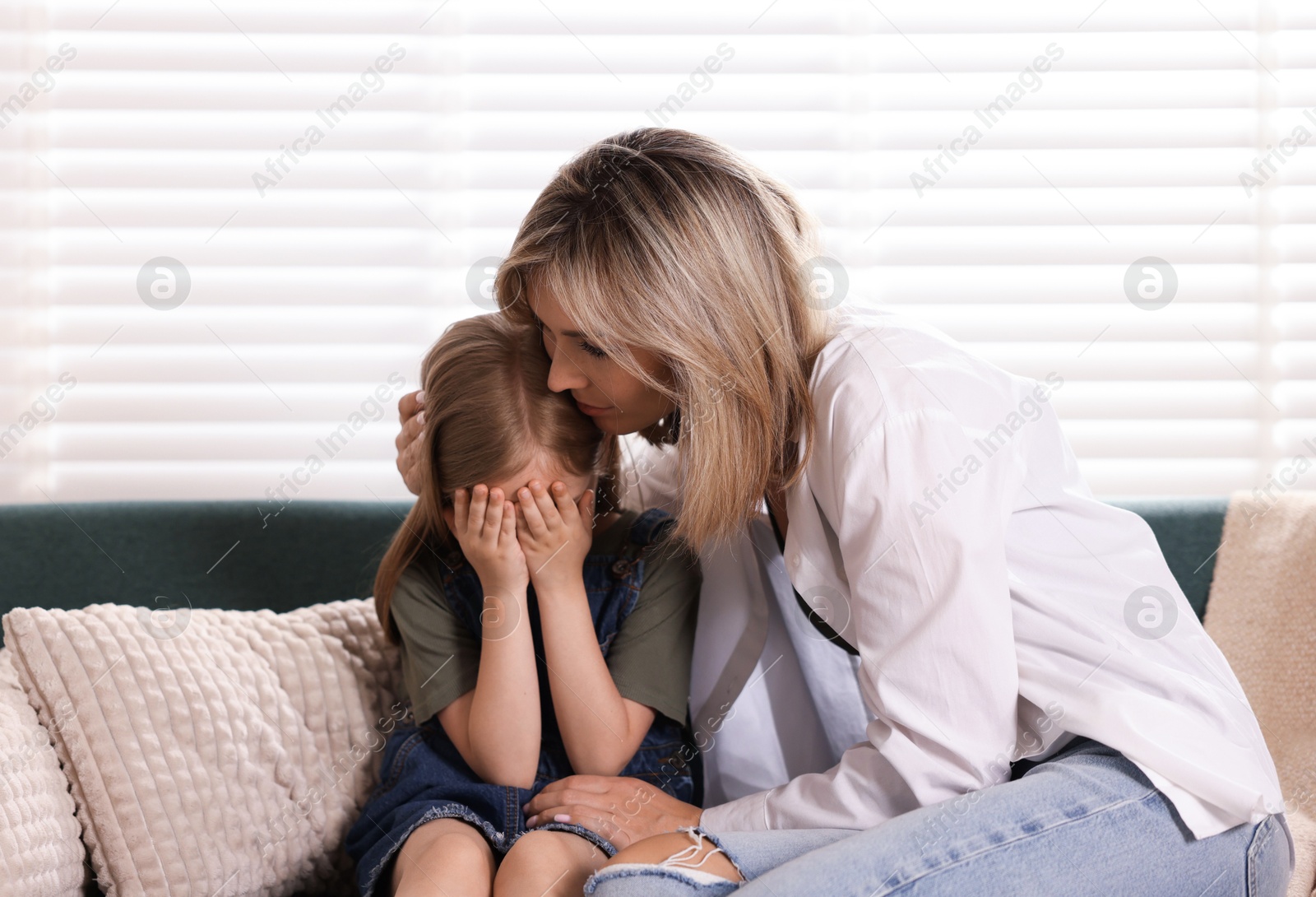 Mother apologizing to her crying daughter on sofa at home Photo of Mother apologizing to her crying daughter on sofa at home