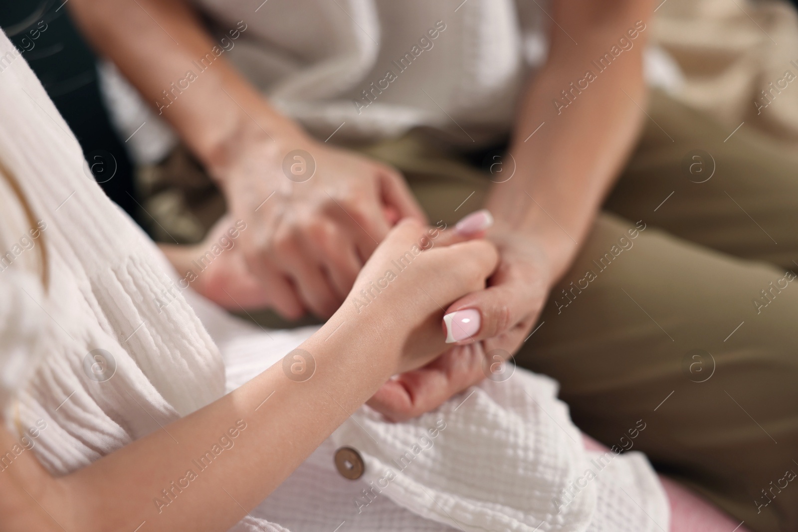 Mother with her daughter holding hands after apology indoors, closeup Photo of Mother with her daughter holding hands after apology indoors, closeup