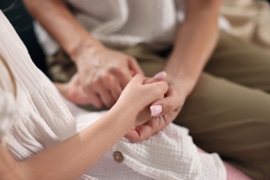 Photo of Mother with her daughter holding hands after apology indoors, closeup