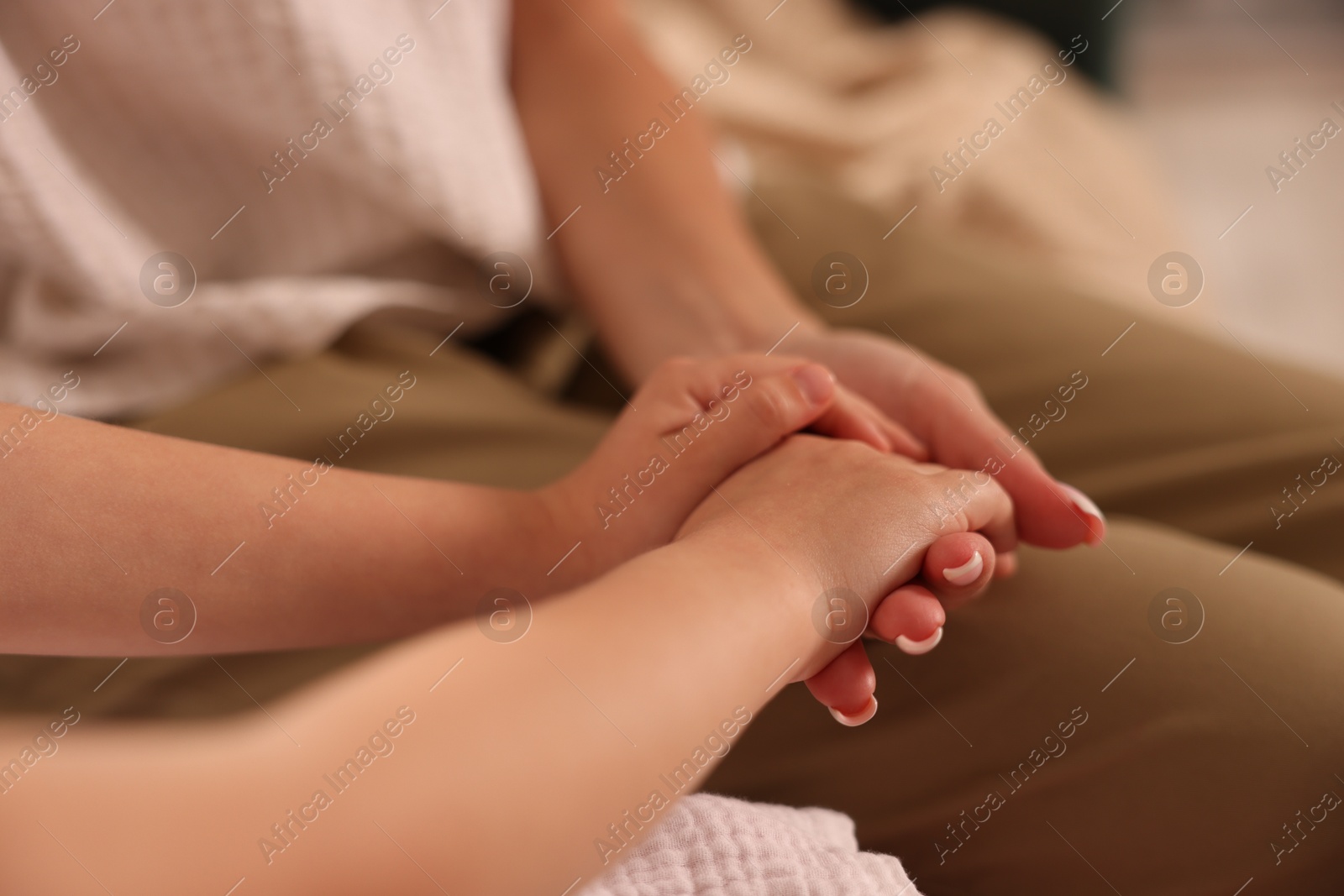Mother with her daughter holding hands after apology indoors, closeup Photo of Mother with her daughter holding hands after apology indoors, closeup