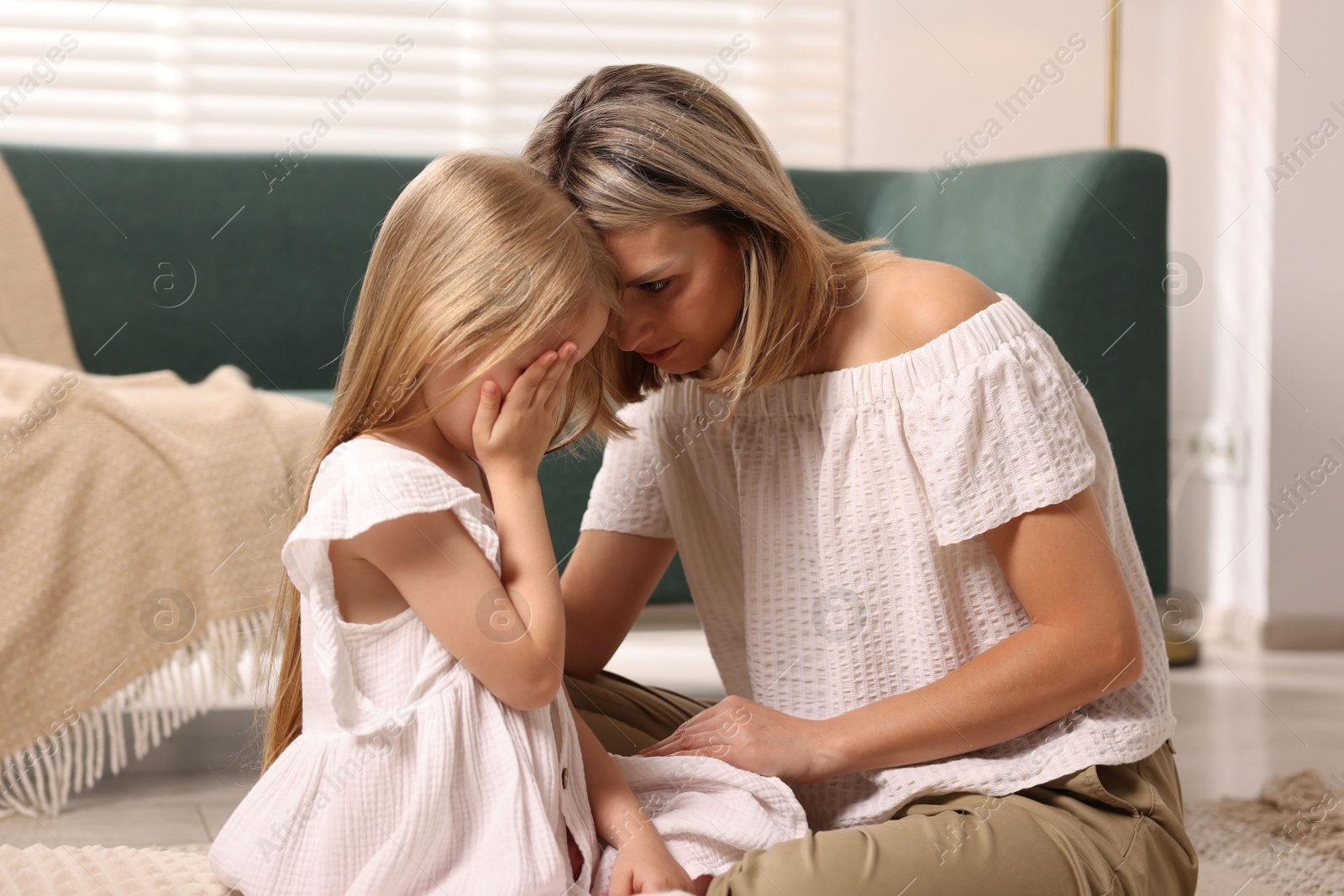 Photo of Mother apologizing to her crying daughter at home