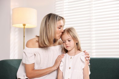 Photo of Mother kissing her sad daughter after apology at home