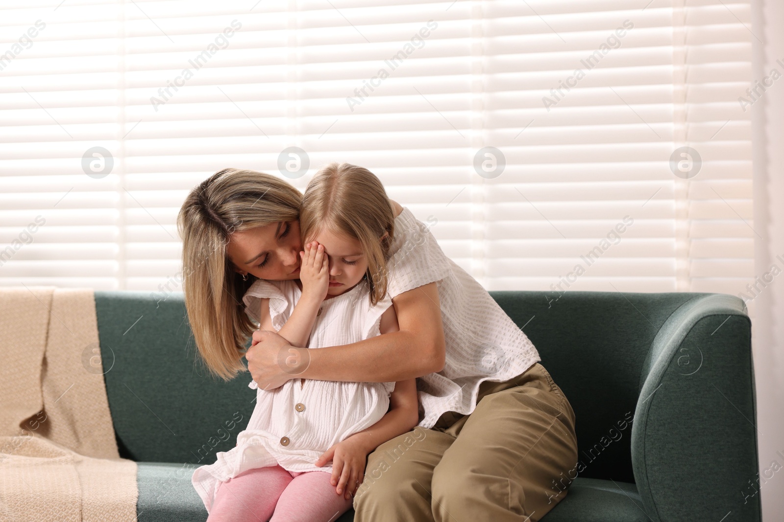 Mother apologizing to her crying daughter on sofa at home Photo of Mother apologizing to her crying daughter on sofa at home