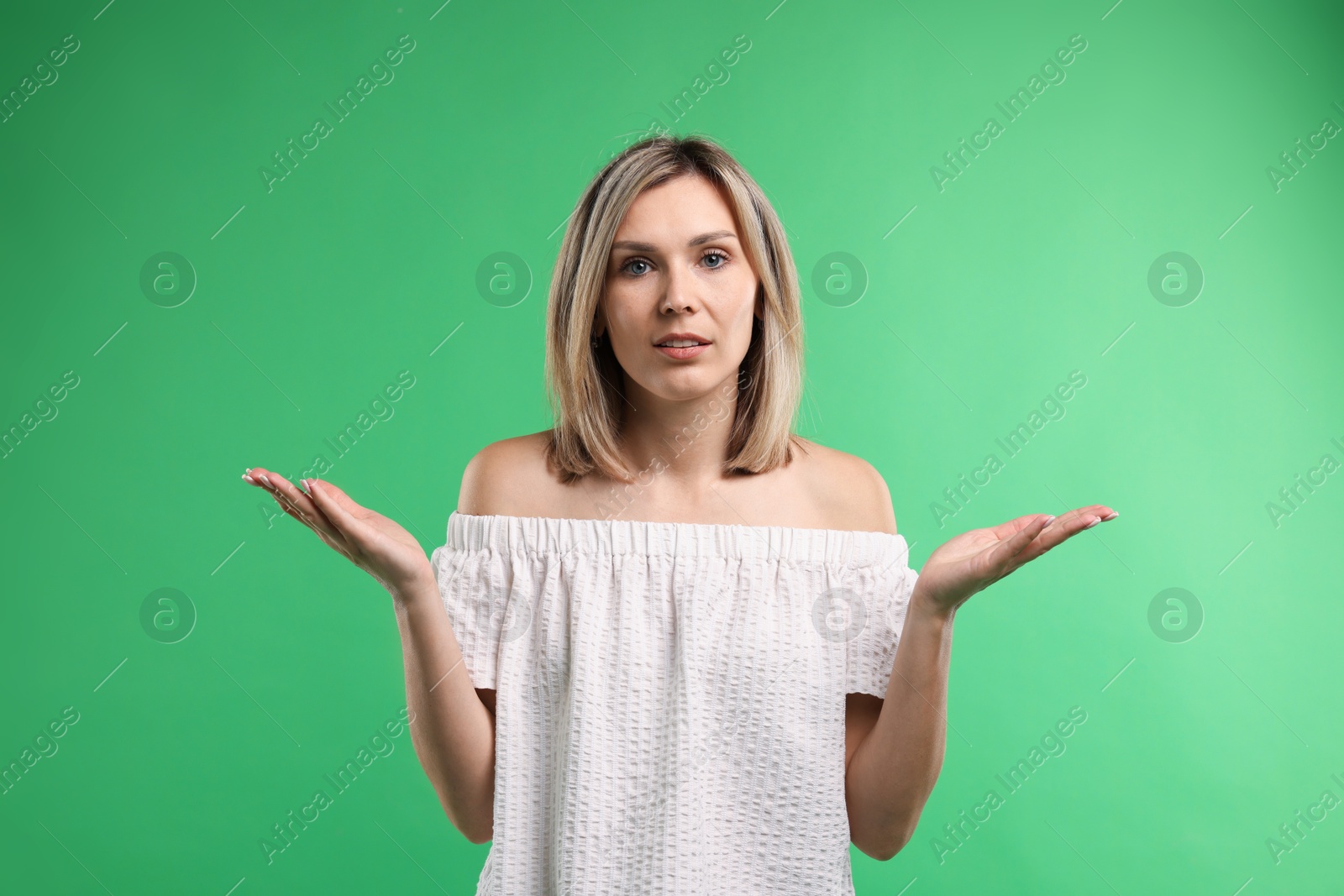 Photo of Portrait of confused woman apologizing on green background