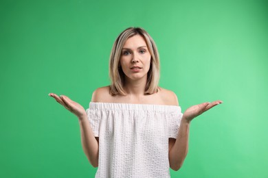 Photo of Portrait of confused woman apologizing on green background
