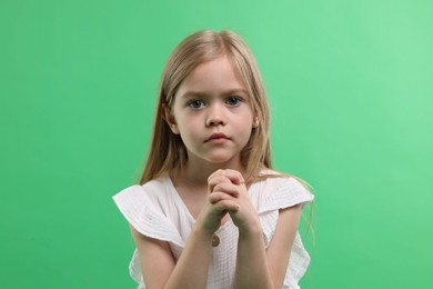 Photo of Portrait of little girl apologizing on green background