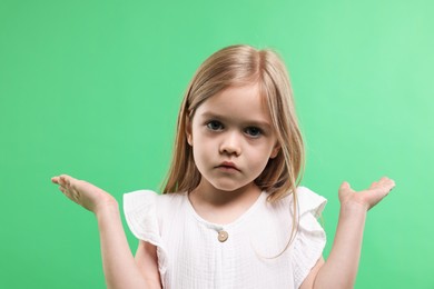 Photo of Portrait of confused little girl apologizing on green background