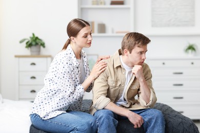 Photo of Young woman apologizing to her offended boyfriend on bed at home