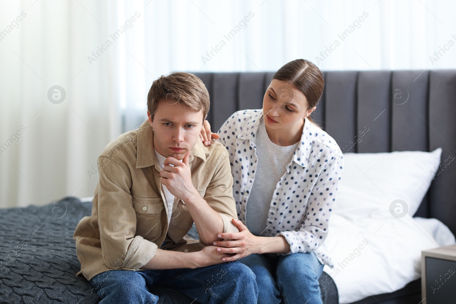 Young woman apologizing to her offended boyfriend on bed at home Photo of Young woman apologizing to her offended boyfriend on bed at home