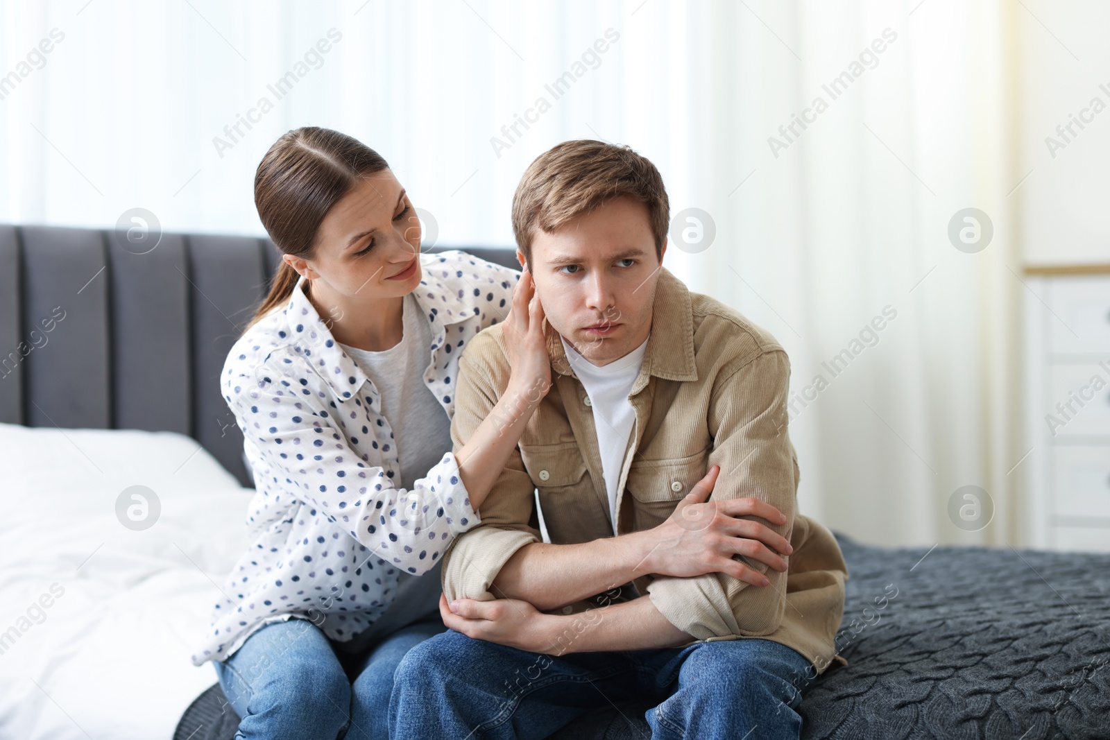 Young woman apologizing to her offended boyfriend on bed at home Photo of Young woman apologizing to her offended boyfriend on bed at home