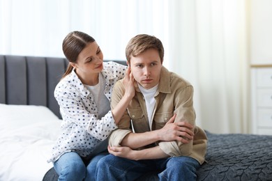 Photo of Young woman apologizing to her offended boyfriend on bed at home