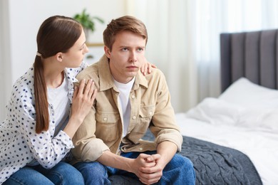 Photo of Young woman apologizing to her offended boyfriend on bed at home