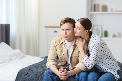 Photo of Young woman apologizing to her offended boyfriend on bed at home. Space for text