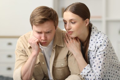 Photo of Young woman apologizing to her offended boyfriend at home