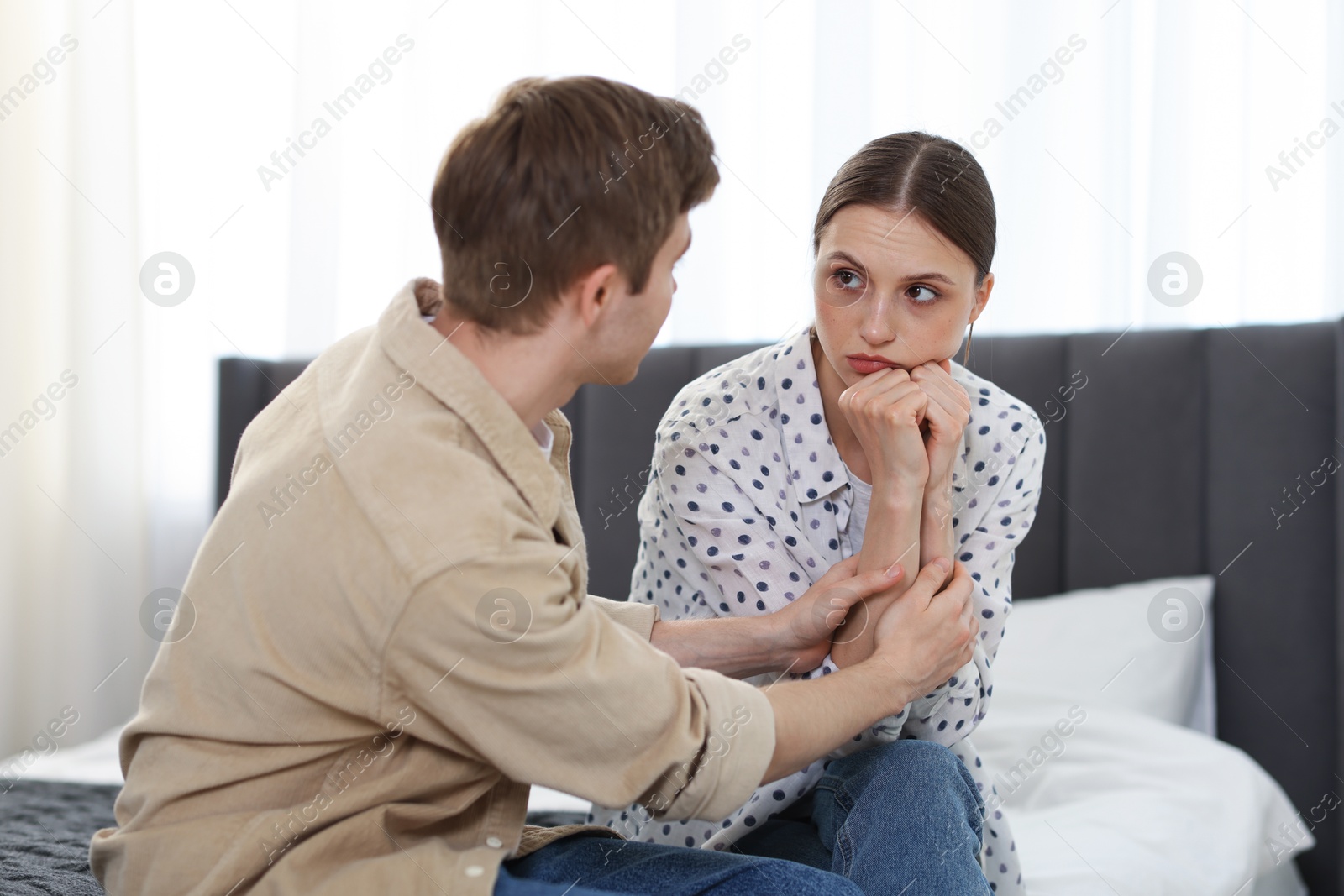 Man apologizing to his offended girlfriend on bed at home Photo of Man apologizing to his offended girlfriend on bed at home
