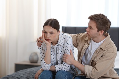 Photo of Man apologizing to his offended girlfriend on bed at home