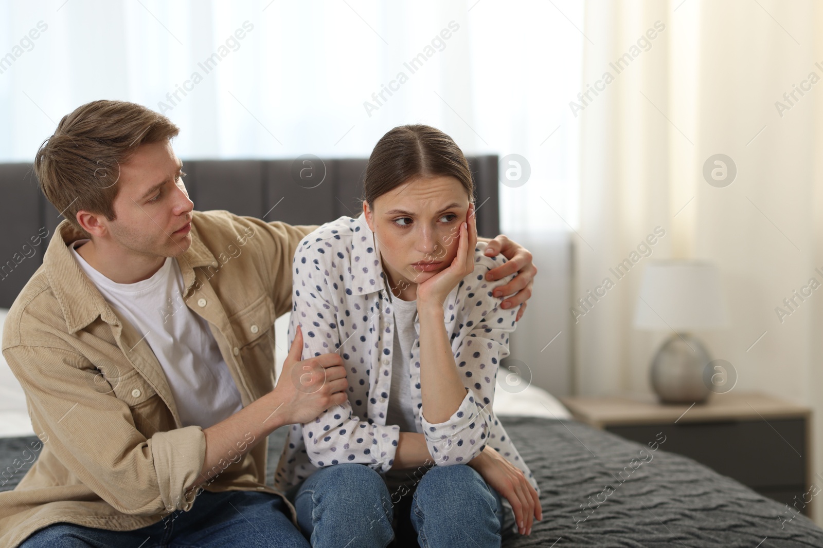 Photo of Man apologizing to his offended girlfriend on bed at home