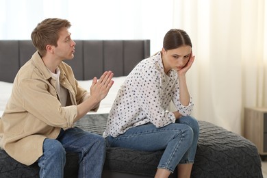 Photo of Man apologizing to his offended girlfriend on bed at home