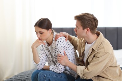 Photo of Man apologizing to his offended girlfriend on bed at home